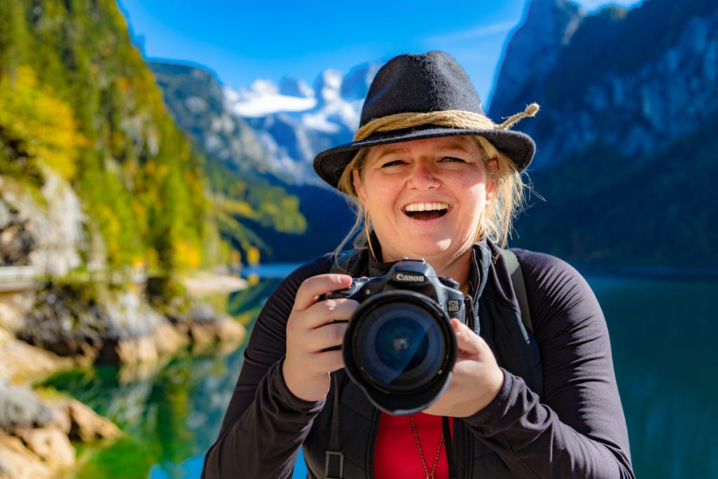 Foto von blonder Frau mit Kamera in der Hand in Berglandschaft