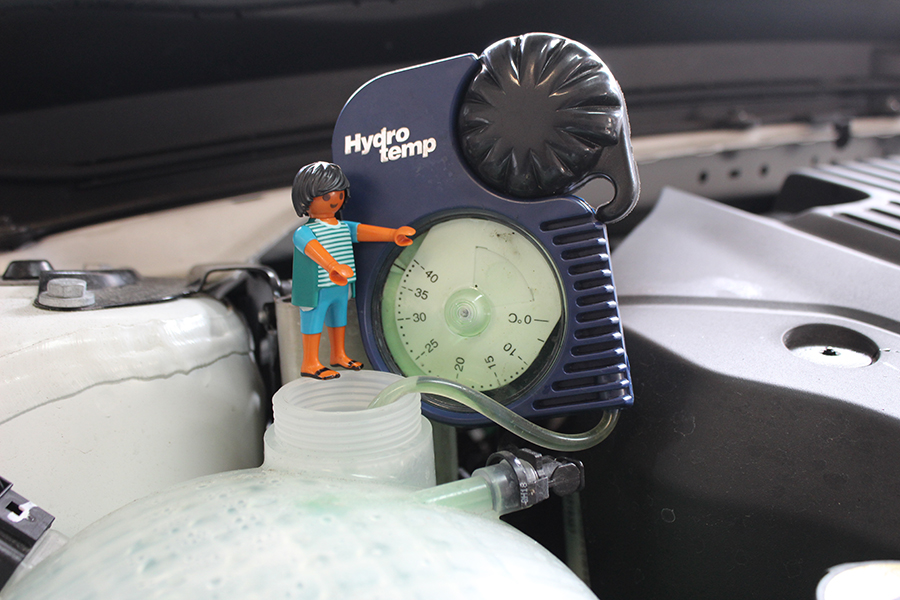 Playmobilmännchen sitzt auf Behälter für Kühlflüssigkeit, an dem ein Testgerät angebunden ist